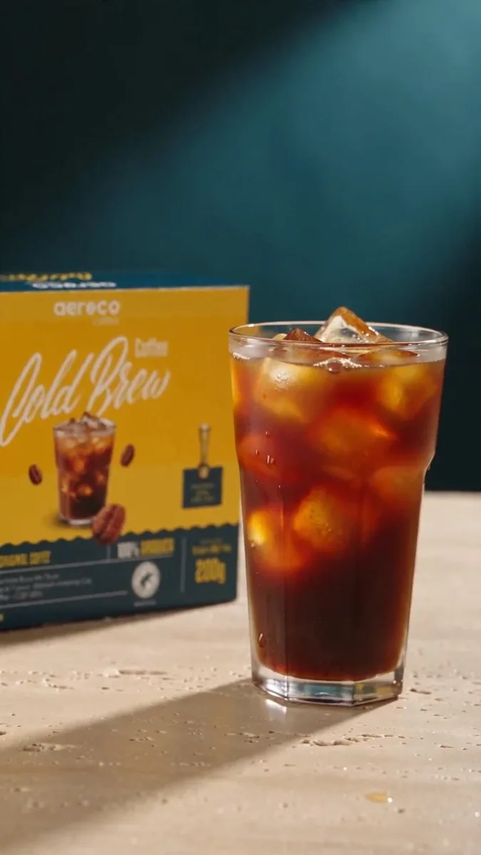 Poster for Aeroco: First Contact. A glass of cold brew and ice beside the yellow Aeroco carton in warm light.
